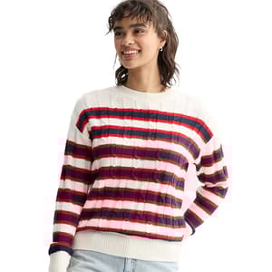 A person wears a striped sweater with red, white, and blue horizontal lines and light-colored jeans.