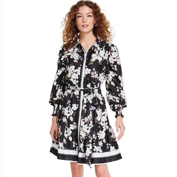 Anne Klein Printed Tiered Shirtdress features a black base with white floral print, long puffed sleeves, a collared neckline, zip closure, and a tiered skirt with a belted waist.