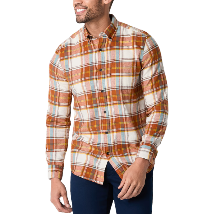 A man is wearing a long-sleeved plaid flannel shirt with hues of orange, yellow, and white, accented with blue pants.