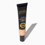 Black tube of Laura Geller foundation with peach-colored label, offering SPF 50 protection and skincare-infused benefits.