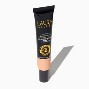 Black tube of Laura Geller foundation with peach-colored label, offering SPF 50 protection and skincare-infused benefits.