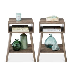 Two wooden side tables with open shelves and four legs, each holding books and decorative items like glass bottles and candles.