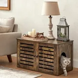 Rustic wooden cabinet with a side opening for pets; decorated with a candle tray, table lamp, and metal lantern. Beige sofa and patterned rug on the side.