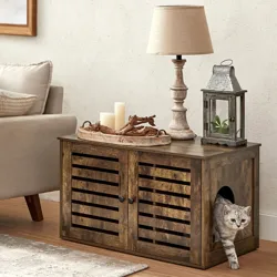Rustic wooden cabinet with a side opening for pets; decorated with a candle tray, table lamp, and metal lantern. Beige sofa and patterned rug on the side.