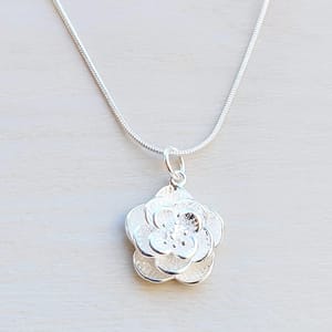 A silver necklace features a pendant designed as a layered flower with textured petals, attached to a sleek chain.