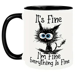 A white mug with a black handle displays a cartoon cat with wide eyes and messy fur. The text reads: \“It's Fine, I'm Fine, Everything Is Fine.\“