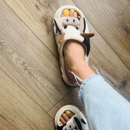 A pair of sandals with an animal face design, worn with jeans.