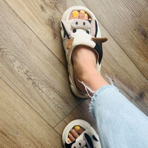 A pair of sandals with an animal face design, worn with jeans.