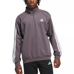A person is wearing a dark gray Adidas half-zip pullover with white striped sleeves and a logo on the chest, paired with black pants featuring the same logo.