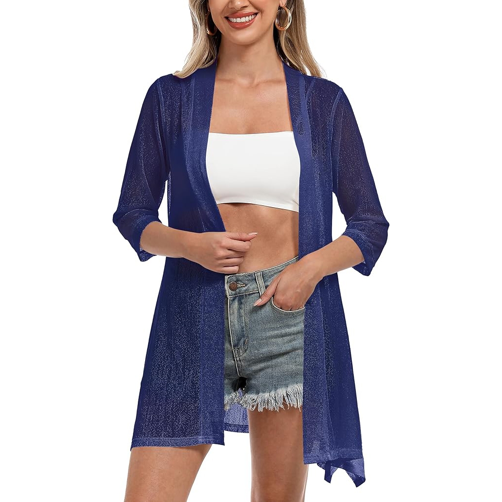 A woman is wearing a sheer blue kimono-style cover-up with 3/4 sleeves, paired with a white tube top and frayed denim shorts.