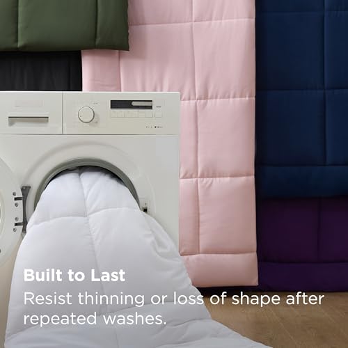 A washing machine is partially covered by a white quilt or blanket being washed. Background displays pink, green, black, and blue quilted blankets. Text states it resists thinning or shape loss after washing.