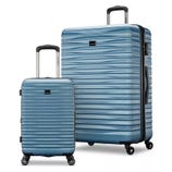 Two blue hard-shell suitcases with textured surfaces and telescopic handles, one larger and one carry-on size, each with four spinner wheels.