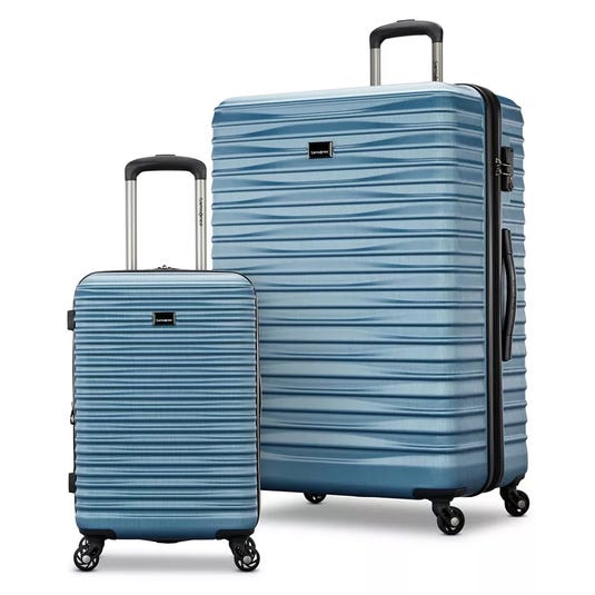 Two blue hard-shell suitcases with textured surfaces and telescopic handles, one larger and one carry-on size, each with four spinner wheels.