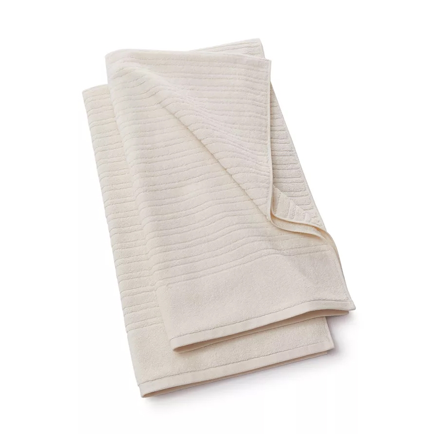 A cream-colored bath towel with a subtle striped texture, folded neatly.