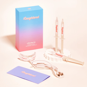 Laughland whitening kit includes two whitening syringes, a mouth tray, a USB charging cable, and a guide. The packaging is gradient blue to pink.