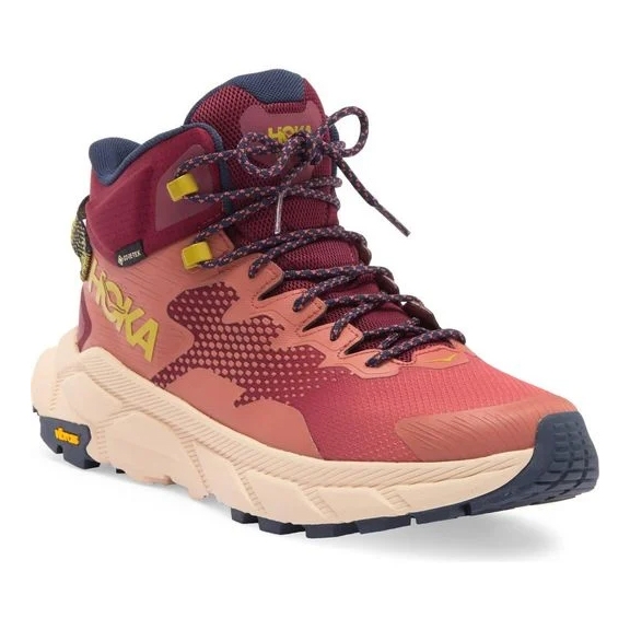 The shoes are high-top hiking boots in red and navy with yellow accents, featuring a lugged sole for traction and the Hoka brand logo.