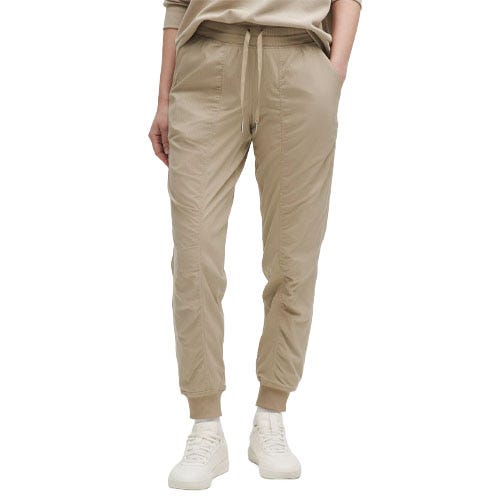 Beige jogger pants with an elastic waistband, drawstring, and cuffed ankles, paired with white sneakers.