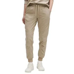Beige jogger pants with an elastic waistband, drawstring, and cuffed ankles, paired with white sneakers.