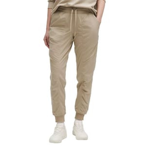 Beige jogger pants with an elastic waistband, drawstring, and cuffed ankles, paired with white sneakers.