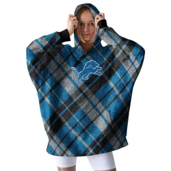 A woman wears a cozy plaid hoodie featuring a blue lion logo, paired with white leggings.