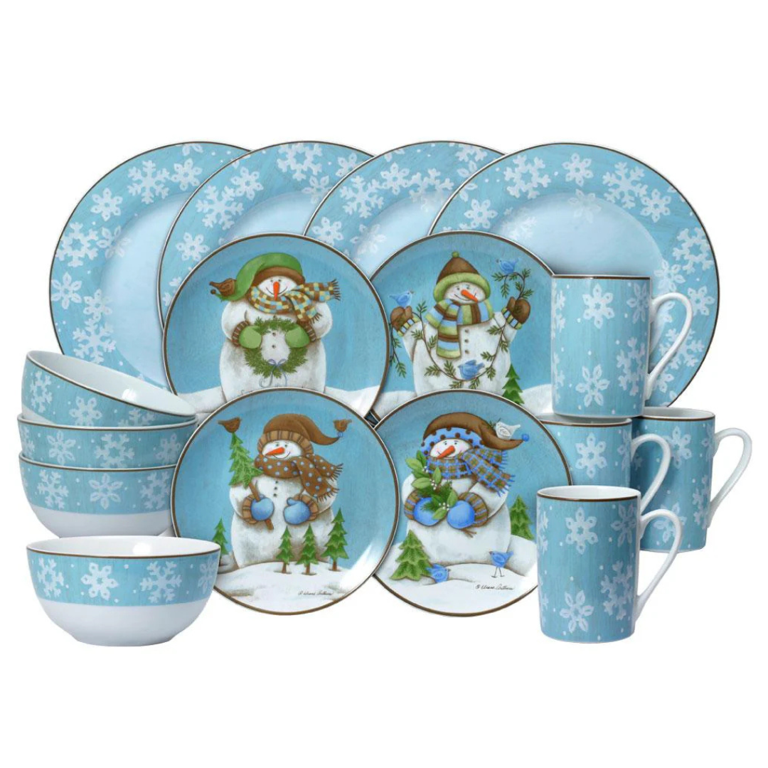 A dinnerware set featuring snowmen and snowflake designs on a blue background, including plates, bowls, and mugs.