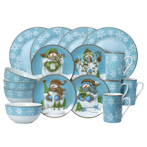 A dinnerware set featuring snowmen and snowflake designs on a blue background, including plates, bowls, and mugs.