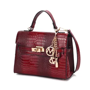 A red crocodile-pattern leather handbag with a top handle and shoulder strap, featuring gold-tone hardware and decorative charms.