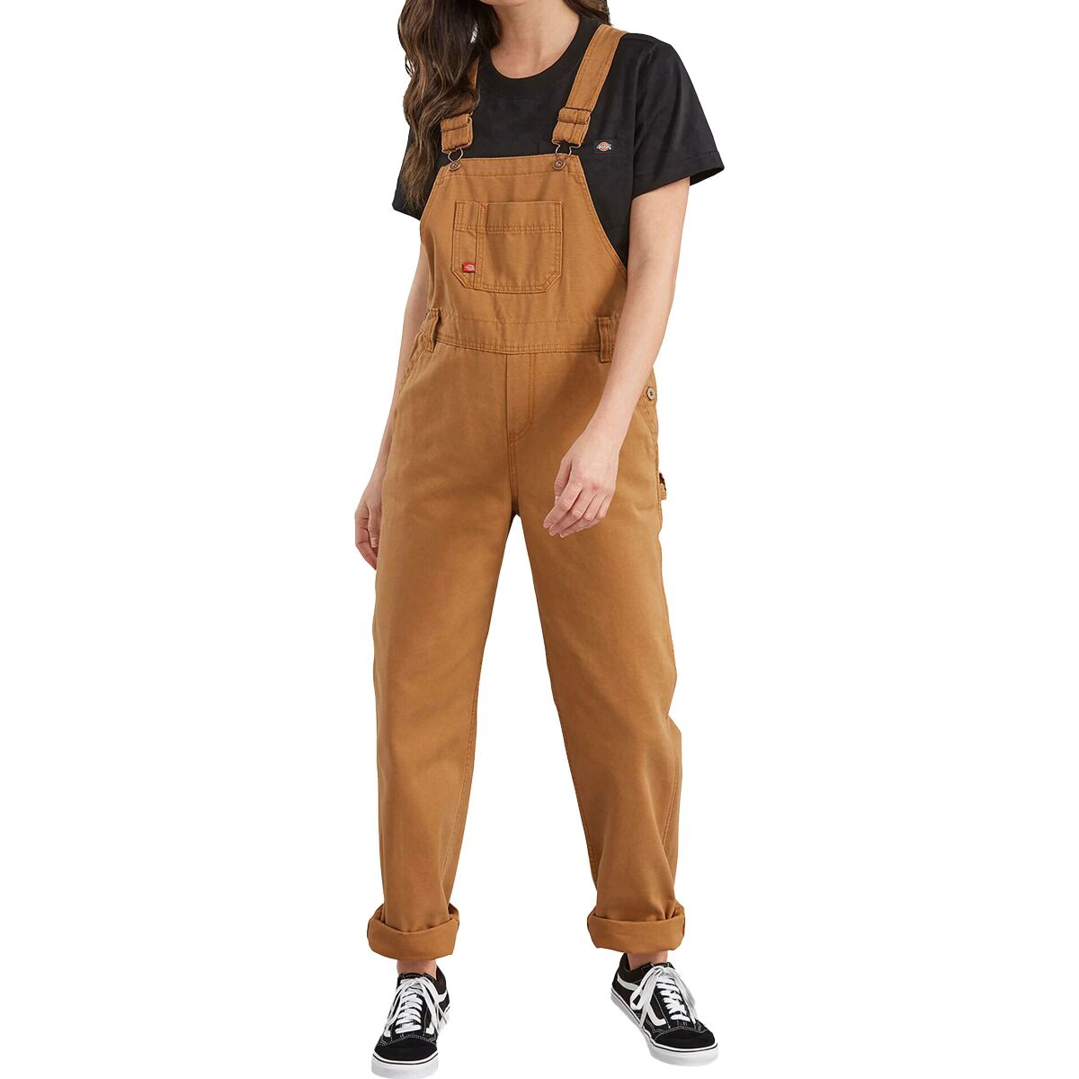 Brown, relaxed-fit overalls for women by Dickies with adjustable straps, a chest pocket, and side button closures. Paired with a black t-shirt and black sneakers.