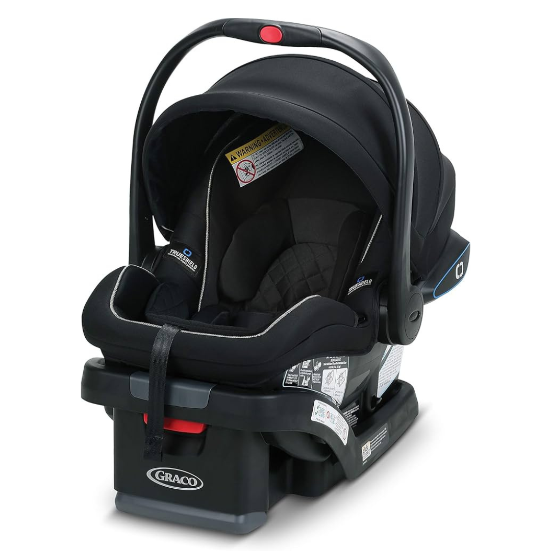 A Graco infant car seat with TrueShield technology, featuring a black design, a handle for carrying, and safety warning labels.