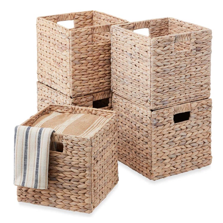 Set of four woven storage baskets with built-in handles; one basket contains two striped, folded towels.