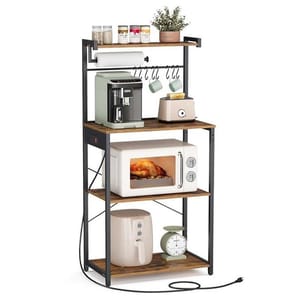 A multi-tiered baker's rack featuring a top shelf with jars and a potted plant, a middle shelf with a coffee maker and toaster, a third shelf with a microwave containing a roast chicken, and a bottom shelf with an air fryer and kitchen scale, with hangers and a paper towel holder.