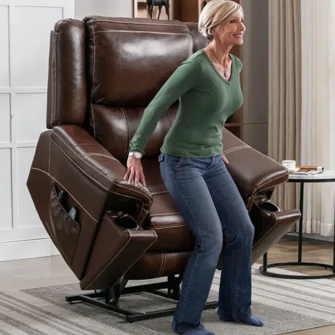 A woman standing next to a brown leather recliner chair with extended footrest.