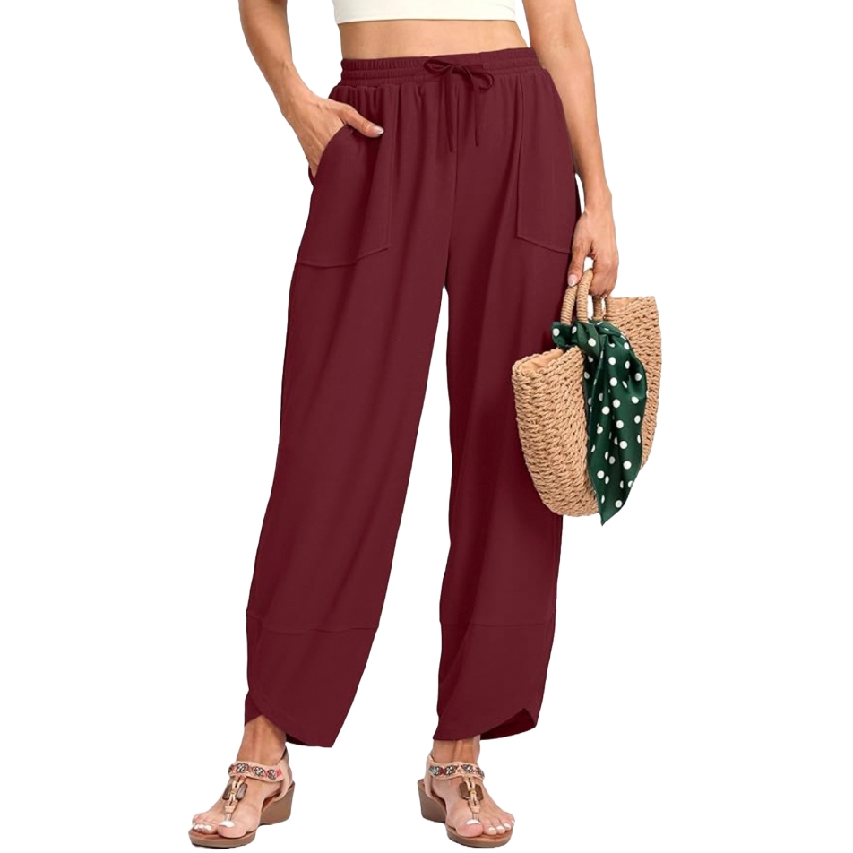 Women's wide-leg pants in deep maroon, featuring a drawstring waist and large front pockets. Styled with open-toe sandals and accessorized with a straw handbag adorned with a green polka dot scarf.