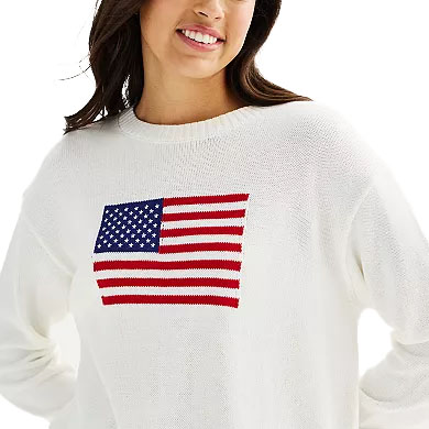 A woman is wearing a white sweater featuring a knitted American flag design on the front.
