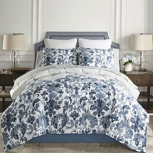 A bed with a blue and white floral-patterned comforter, matching pillows, and neutrally styled lamps on side tables.