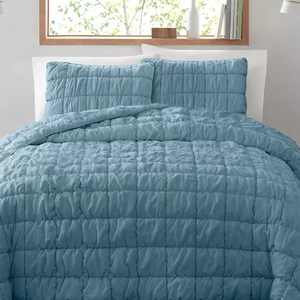 A quilted set with a textured, puff design in a muted blue shade, consisting of a queen-size comforter and two matching pillow shams.