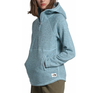 Light blue hooded pullover fleece with a half-zip front and hand pockets, featuring a small North Face logo near the pocket. Worn with olive green pants.