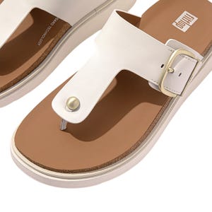White leather toe-post sandals with a gold buckle on the strap, featuring a cushioned brown footbed and thick white sole, designed for comfort and support.
