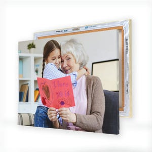 A canvas print displays a touching image of a young girl hugging an elderly woman while holding a handmade card that reads \“I love you.\“