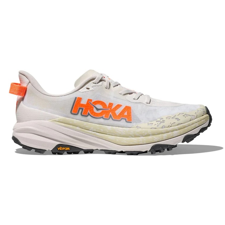 A Hoka running shoe featuring a beige and white color scheme with an orange logo and a Vibram sole, designed for trail running.