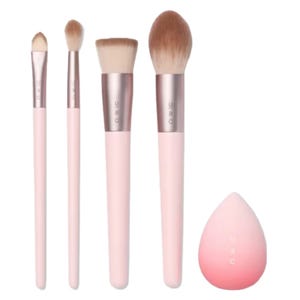 A set of four pink-handled makeup brushes and a pink blending sponge.