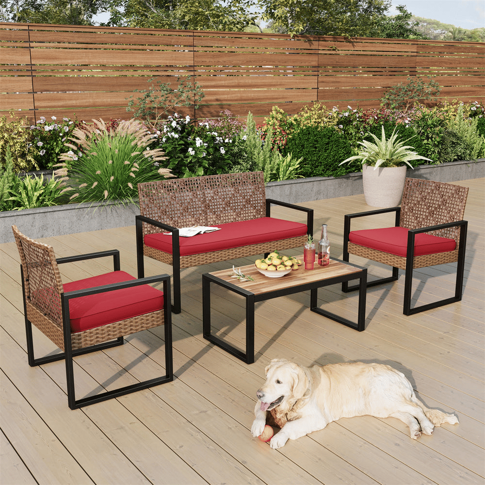 Outdoor patio set with red cushions includes a loveseat, two chairs, and a coffee table with a wooden top, placed on a wooden deck. A dog is lying on the deck.