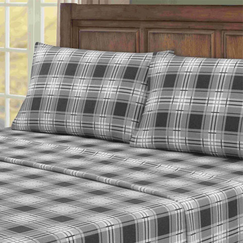 a black and white plaid sheet set on a bed with a dark wood headboard