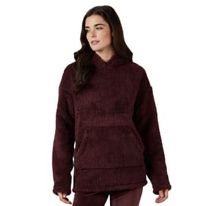 A woman is wearing a burgundy, plush sherpa hoodie with a front kangaroo pocket and relaxed fit.