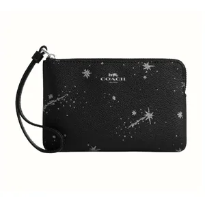 A black Coach wristlet with a celestial pattern of stars and comets, featuring a zip closure and a small strap for carrying.