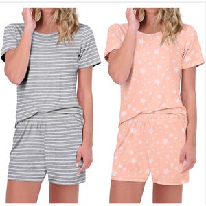 Two short-sleeve pajama sets are shown. One is gray with white stripes, and the other is peach with white star patterns. Both include matching shorts.