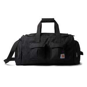 The black Carhartt Utility Duffel Bag features a large main compartment, dual zippered side pockets, and two front flap pockets. It has sturdy dual handles and an adjustable shoulder strap for easy carrying.