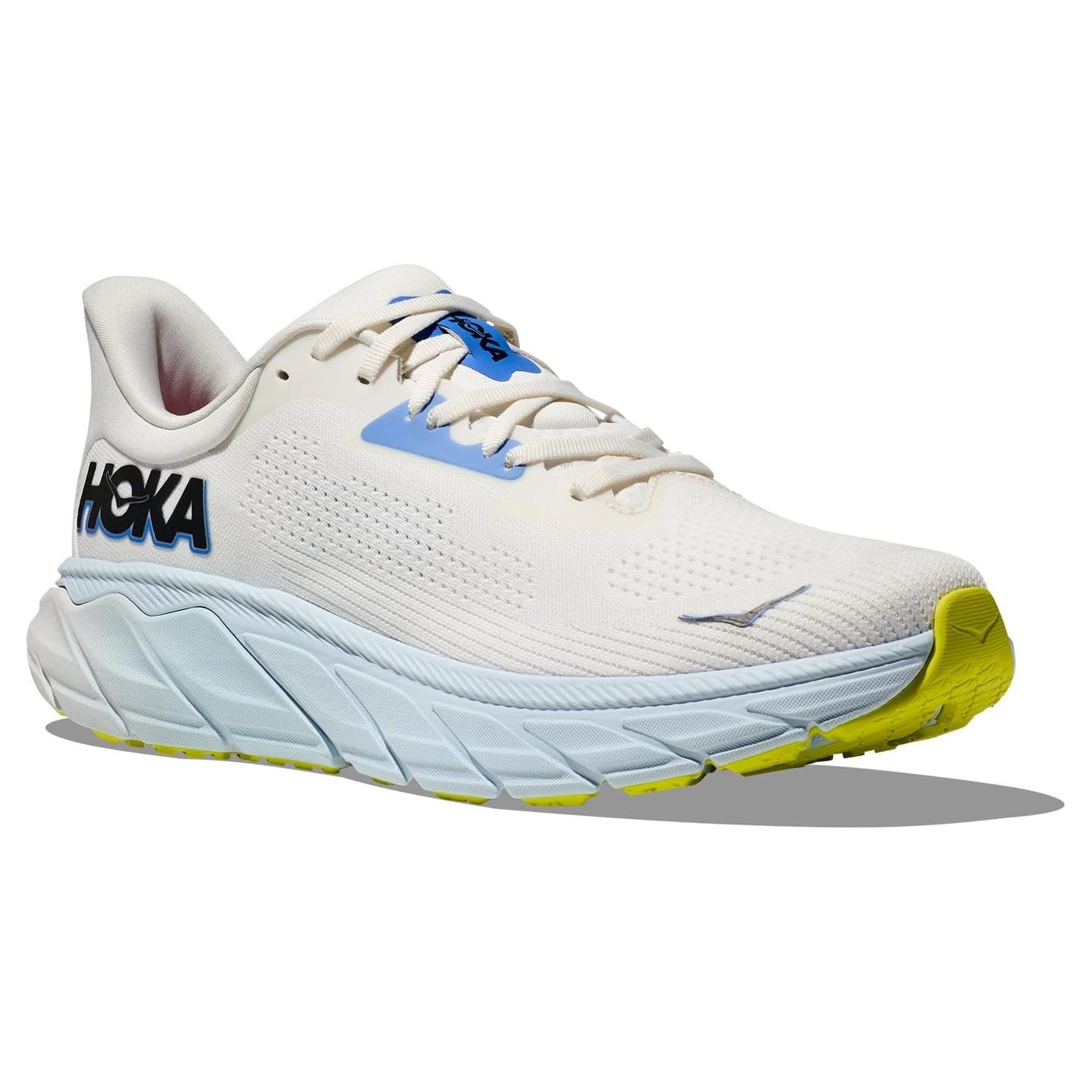 A white Hoka running shoe with blue and yellow accents.