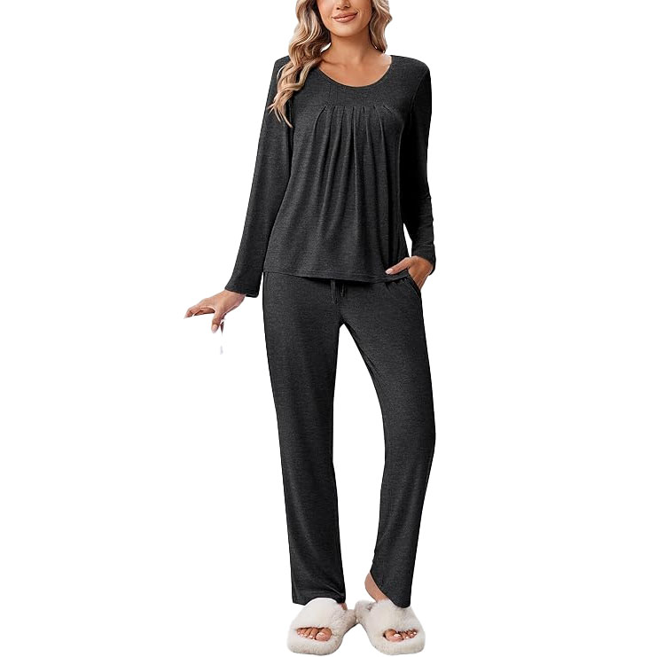 Woman wearing a dark gray, long-sleeve pajama set with pleated detailing, paired with white fluffy slippers.