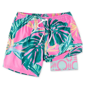 Pink swim trunks with a tropical leaf pattern in green and yellow, featuring an elastic waistband and white drawstring.